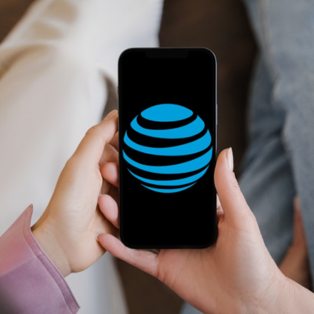 Two people holding a mobile phone with the AT&T logo on the screen
