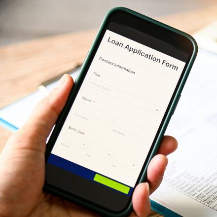 A person holding a phone depicting a loan application form asking for personally identifiable information