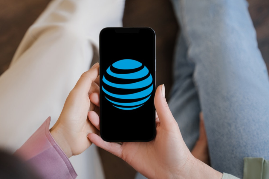 Two people holding a mobile phone with the AT&T logo on the screen