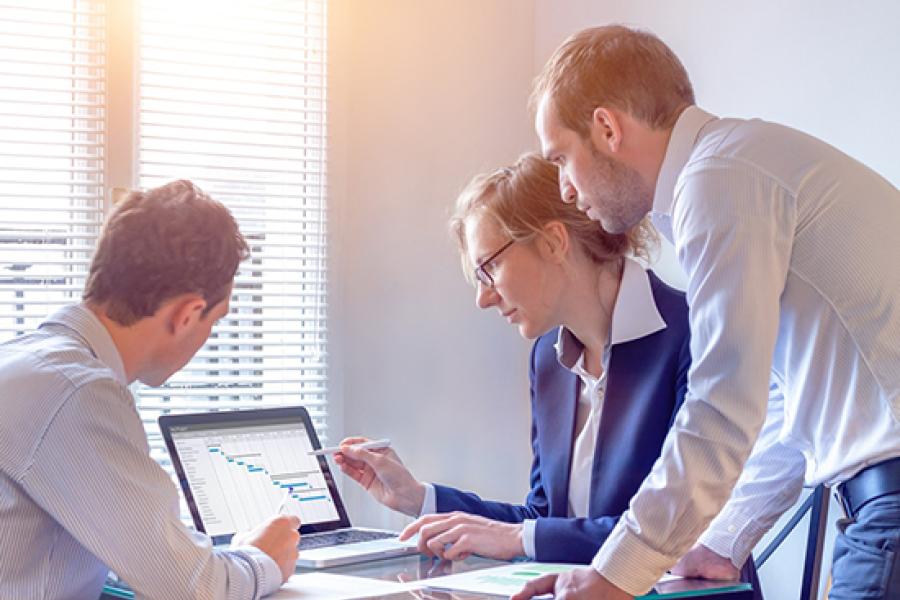 Three people looking at a gantt chart